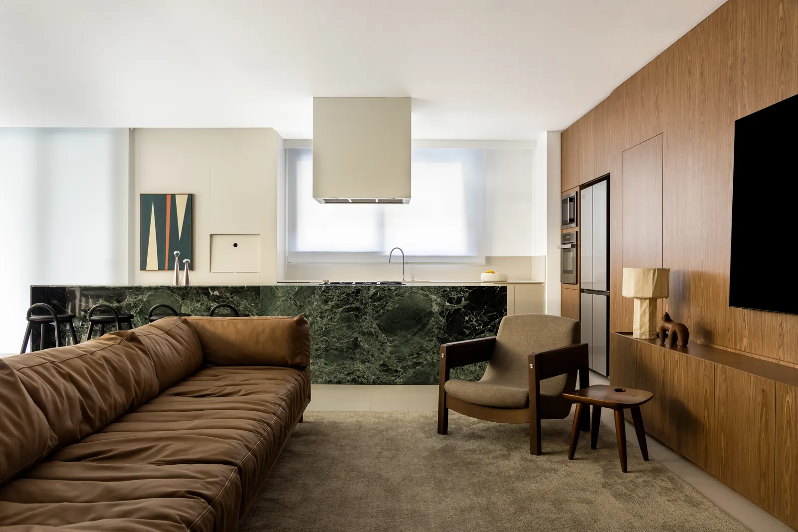 sala do apartamento terra: sofá de couro, bancada de mármore verde e painel de madeira